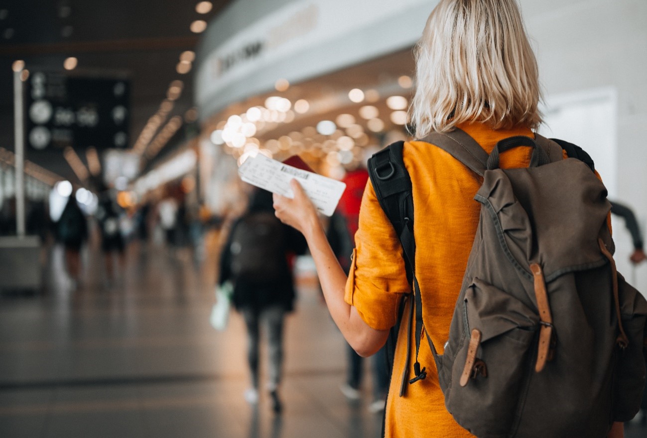 Mulher no aeroporto com mala e bilhete na mão