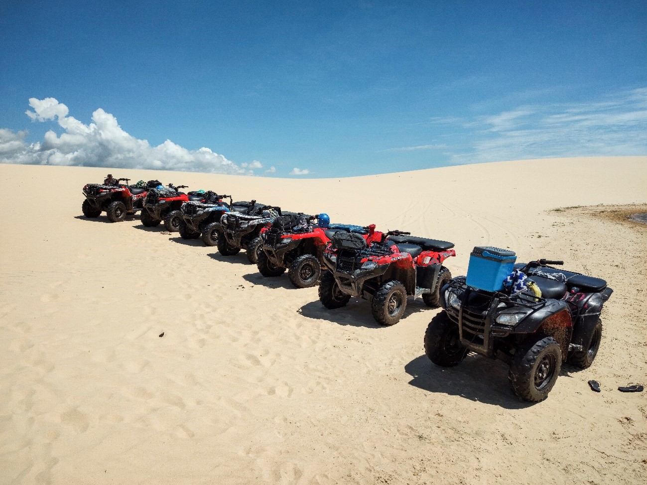 Imagem de sete quadriciclos estacionados nas dunas dos Lençóis Maranhenses